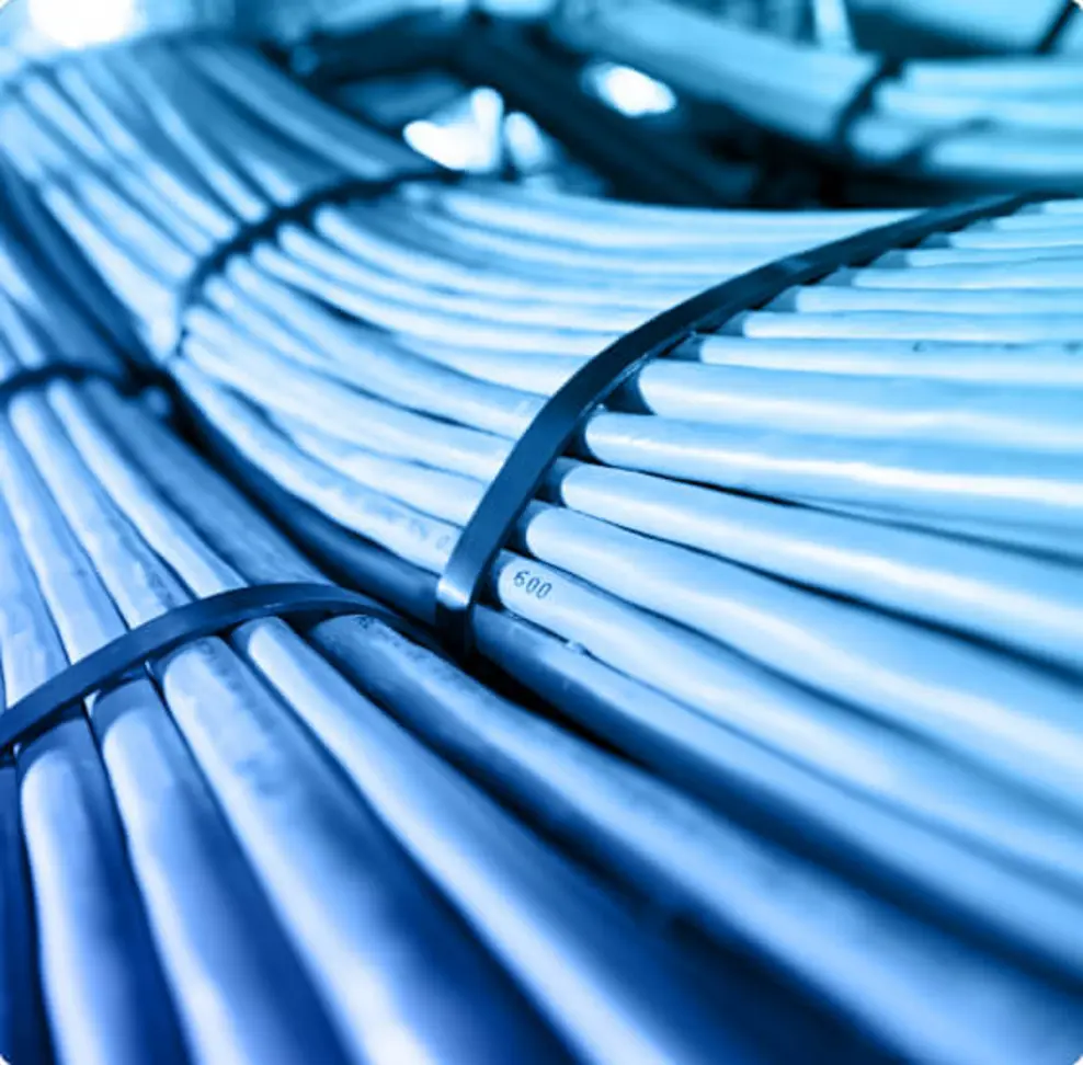 A close-up view of bundled cables or pipes, likely used for electrical or telecommunications purposes. The cables are arranged cylindrically and secured with straps, with a blue-tinted color scheme possibly due to lighting or image processing.