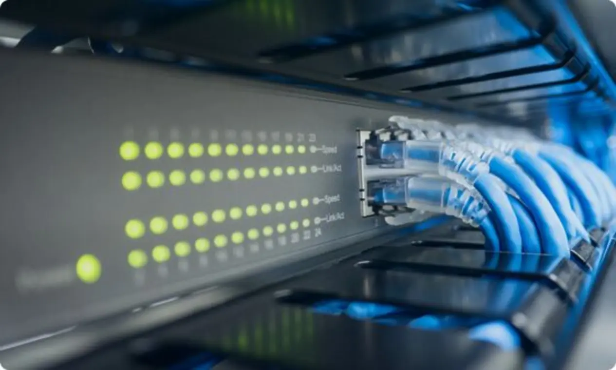 A close-up view of a network switch or patch panel with multiple blue Ethernet cables connected to the ports. A row of LED indicators is visible, showing network activity and connection status through illuminated lights that reflect data transfer activity.