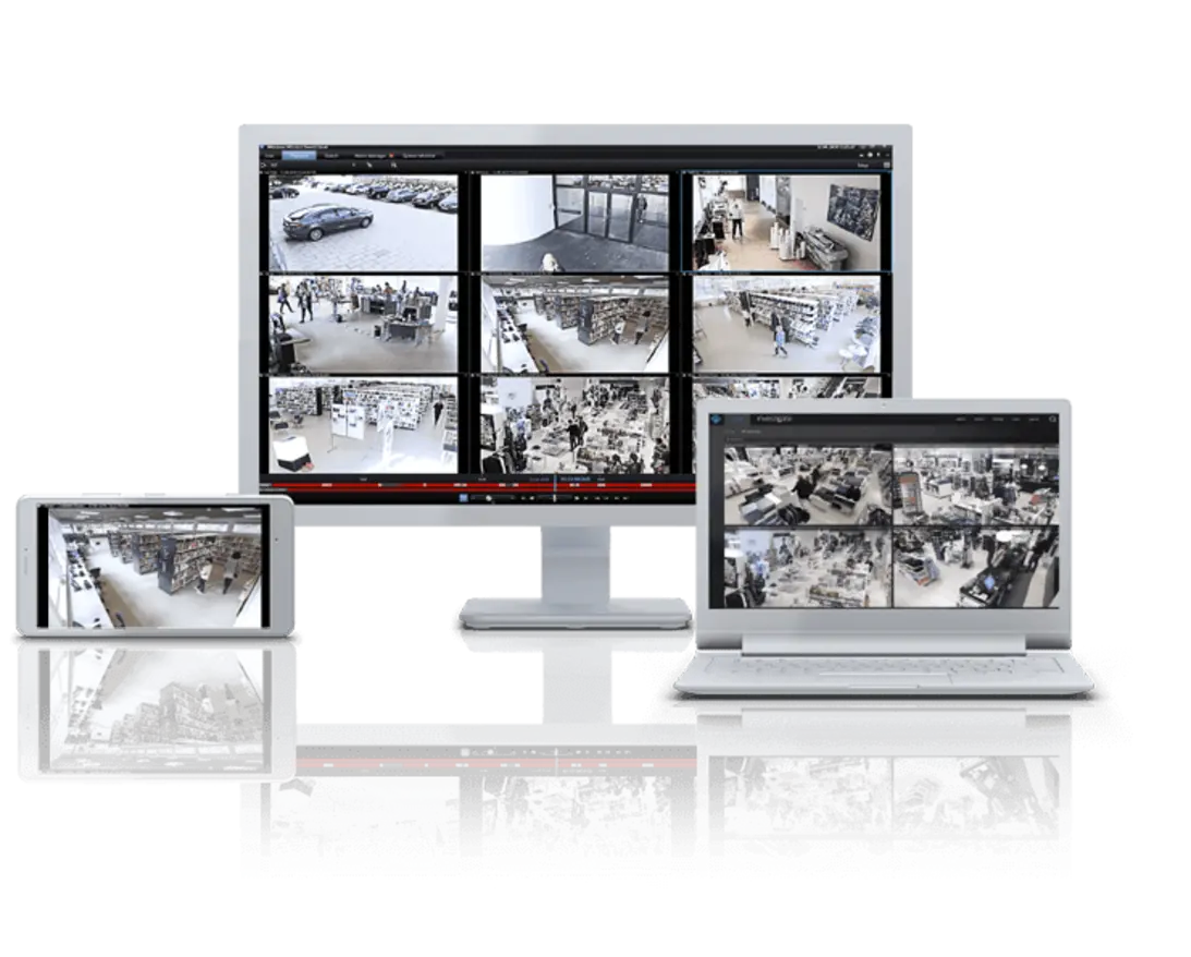 A setup featuring multiple screens displaying security camera footage in a grid layout, including a desktop, laptop, and tablet. The black-and-white feeds show various angles and views, likely from a store, used for monitoring and surveillance purposes.